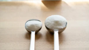 Teaspoon vs tablespoon filled with sugar side by side on a wooden counter